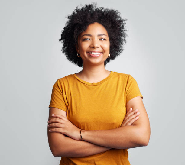 foto de estudio de una hermosa joven sonriendo mientras está de pie sobre un fondo gris - 25 fotografías e imágenes de stock