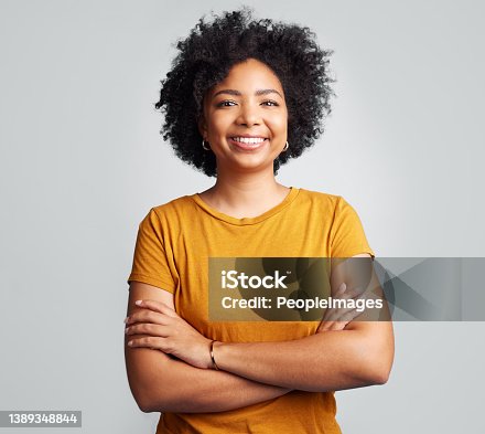 istock Studio shot of a beautiful young woman smiling while standing against a grey background 1389348844