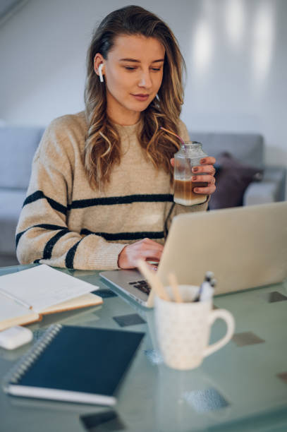 istock Woman using a laptop and drinking coffee with ecology straw at home 1389349909