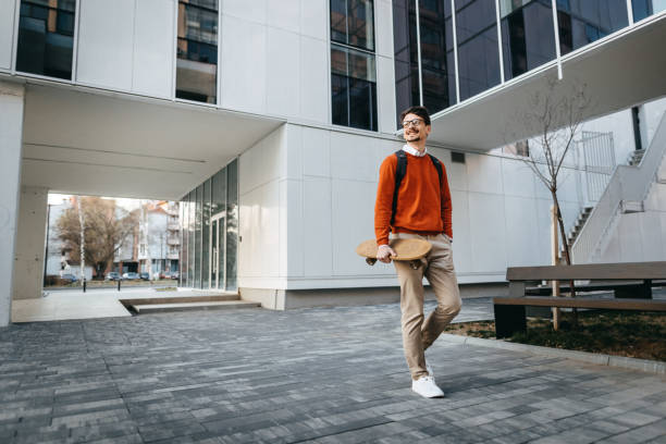 istock Businessman with skateboard walking on street 1389350927