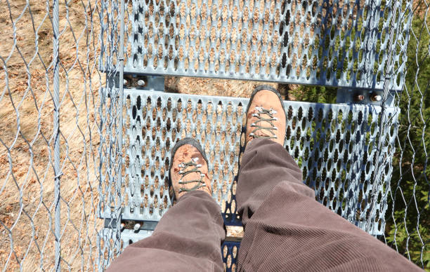 legs of the hiker with boots on while crossing a suspension bridge that almost makes you dizzy