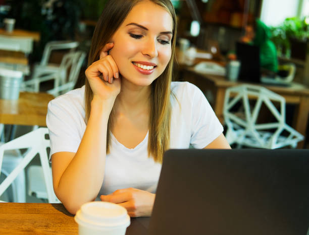 istock Happy young woman drinking coffee and using laptop 1389356001