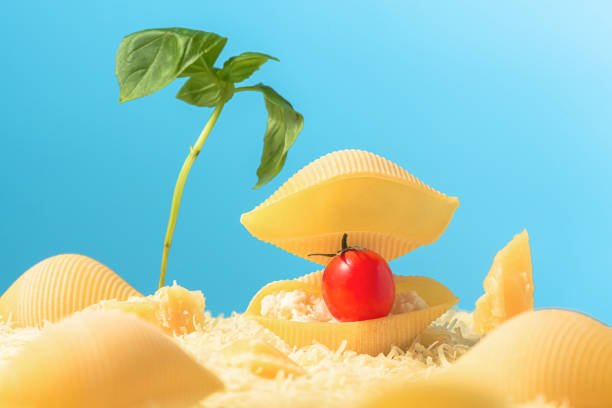 sommerstrand mit muscheln und palmen aus pasta, parmesan und basilikum. kreatives essenskonzept - vibrant color tomato vegetable pasta stock-fotos und bilder