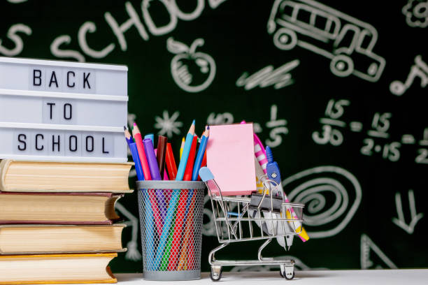 istock Back to school background with books, pencils and globe on white table on a green blackboard background. 1389358483
