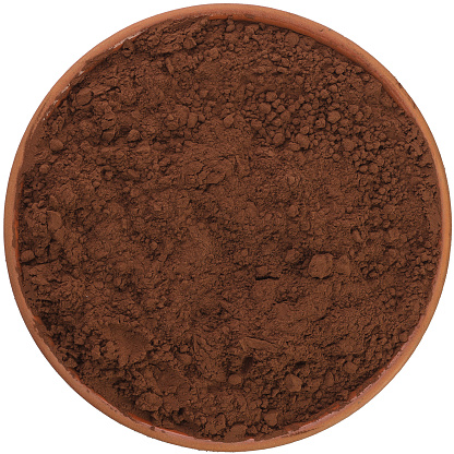 Alkalized cocoa in a brown ceramic bowl isolated on white background. Isolated close-up photo of food close up from above on white background.