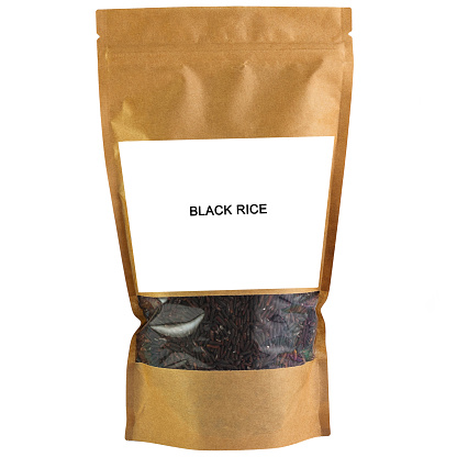 Black rice groats in a brown paper bag. Doy-pack with a plastic window for bulk products. Close-up. White background. Isolated.