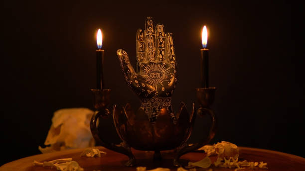 Fortune teller hand or palmistry on the witch table with animal bones. Palmistry with black palm and candles in the candelabra. Magic alchemy spirituality symbol. Palm reading in mystic, occult room.