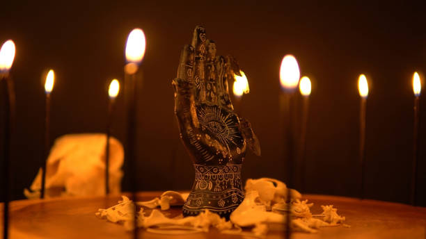 istock Mystical esoteric table with ritual object. Fortune teller palm with black candles on tree trunk surface. Prediction destiny and forecasting future hand reader statue. Occult science and supernatural. 1389363850