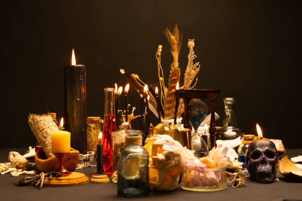 istock Occult and esoteric witch doctor still life. Selective focus. Halloween background with magic objects. Black candles skull, crystal stones, and potions vials on witch table. Mystic witchery with weeds 1389363859