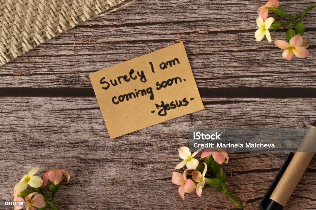 I am coming soon, Jesus Christ's words, a handwritten text quote on wood background with flowers in vintage style I am coming soon, handwritten text quote on wood background with flowers in vintage style. The second coming of the Lord Jesus Christ. The biblical Revelation concept of hope, love, and faith in God. Jesus Christ Stock Photo