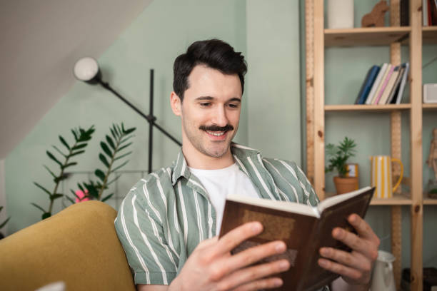 istock Young man concentrated on reading, relaxing on the sofa 1389364922