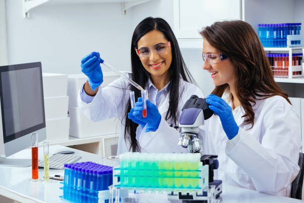 istock Two beautiful young female scientists working in laboratory with test tubes and microscope doing some research 1389367334