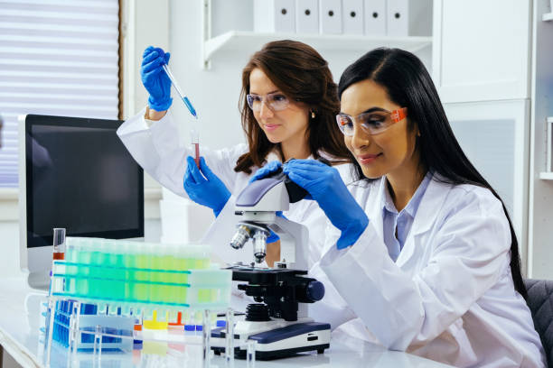 istock Two beautiful young female scientists working in laboratory with test tubes and microscope doing some research 1389367544