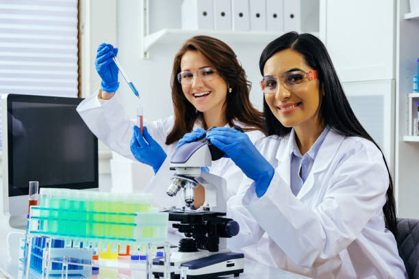 istock Two beautiful young female scientists working in laboratory with test tubes and microscope doing some research 1389367549