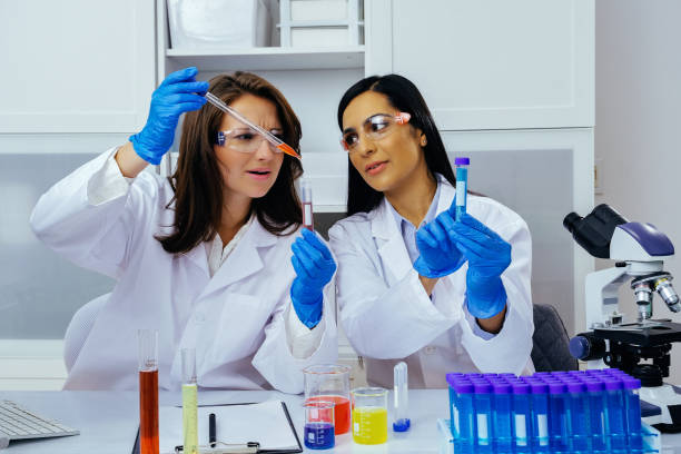 istock Two beautiful young female scientists working in laboratory with test tubes doing some research 1389367555