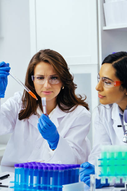 istock Two beautiful young female scientists working in laboratory with test tubes doing some research 1389367565