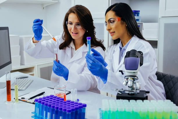 istock Two beautiful young female scientists working in laboratory with test tubes doing some research 1389367596