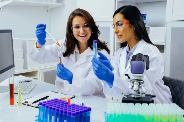 istock Two beautiful young female scientists working in laboratory with test tubes doing some research 1389367599