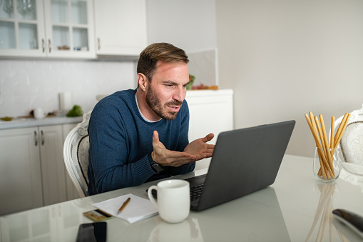 Unhappy man feel distressed with laptop problem. Unhappy dissatisfied businessman looking at laptop screen. Reading bad news in message. Frustrated stressed young man having problem.