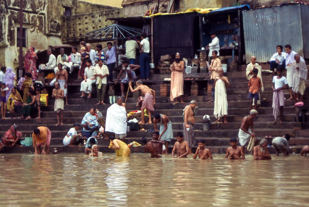 Varanasi, India - aug 14, 1996:  crowds of Hindu faithful perform the ritual purification bath by immersing themselves in the muddy waters of the Ganges in flood.  Vintage photo. Historical archive photo.