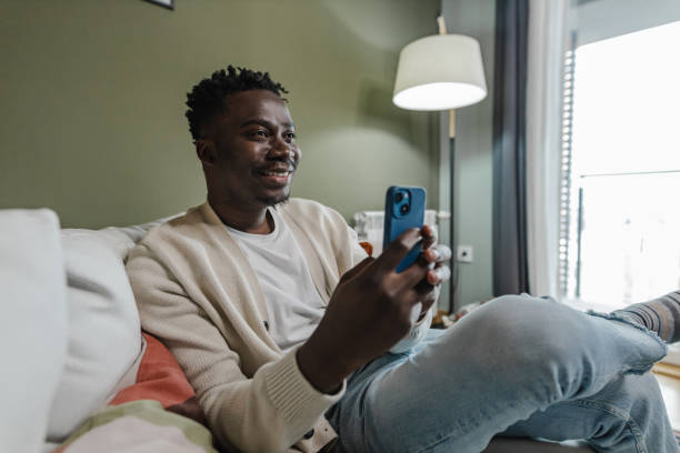 istock Young African-American man using mobile phone at home 1389368872