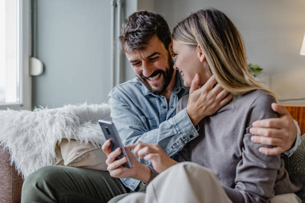 istock Young couple embracing at home and using mobile phone 1389376870