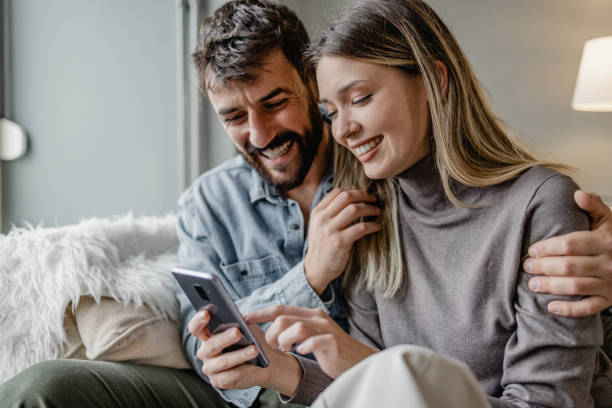 istock Young couple embracing at home and using mobile phone 1389376990