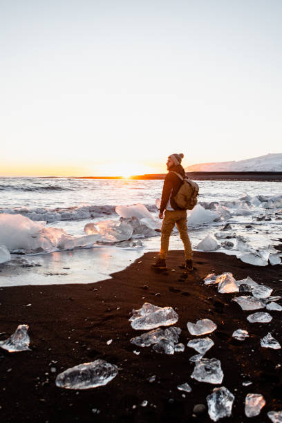 el hombre disfrutando de la puesta de sol en la playa diamond en islandia - travel europe sunset winter fotografías e imágenes de stock