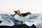 The man lying on the crystal ice on the Diamond beach in Iceland