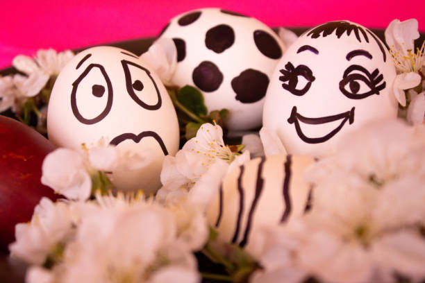 istock Funny Easter eggs with painted faces and white flowers next to them. Celebration. Easter eggs with joyful faces on a plate. Easter with your own hands. Minimal easter holiday concept 1389400594