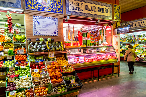 Fruit, vegetable, meat and produce vendors and stalls inside the colorful and vibrant Triana Market or Mercado di Triana in the historic Triana district of the Andalusian city of Seville Spain.