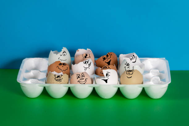 istock Multi colored eggshells with humorous playful faces in an egg carton 1389402750