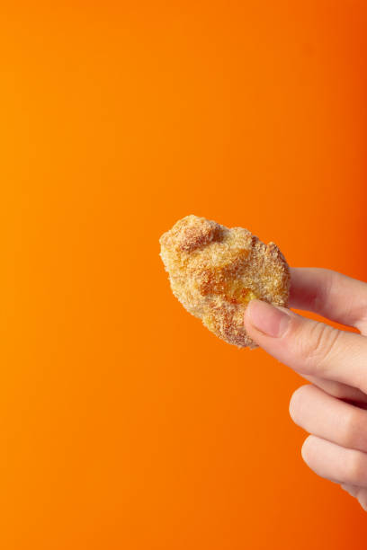 Holding a fried snack chicken nuggets on an orange background in your hand stock photo