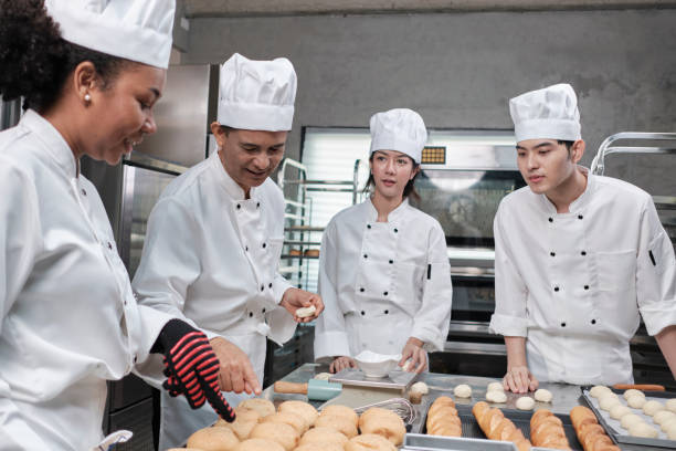 istock Chefs team in uniforms prepare to bake bread and pastry in stainless kitchen. 1389410874