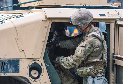 Washington, United States - March 29 2022: United States Marine Corps soldier in uniform with helmet near a armored vehicle humvee, USA or US army troops ready for battle, drills or war in the city, NATO unit force member in Vilnius, Lithuania