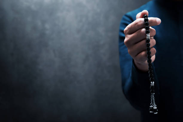 Muslim man praying with rosary beads stock photo