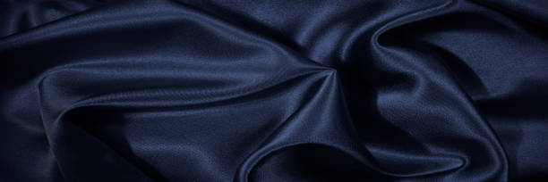 istock Black blue silk, satin. Shiny fabric surface. Beautiful wavy folds. Dark elegant background with space for design. Web banner. 1389422015