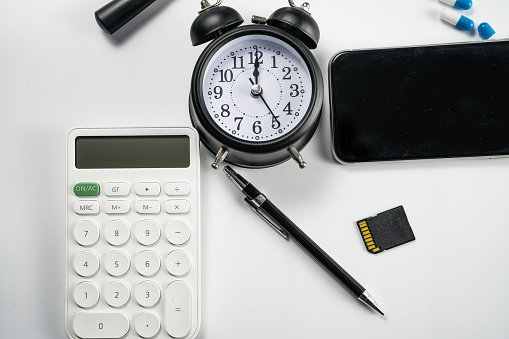 Alarm clock, computer, magnifying glass, calculator and medicine on white background board