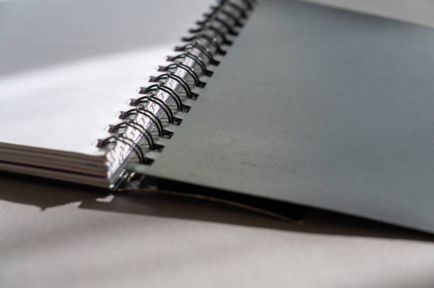 istock Black spring-loaded notebook against a gray background. Close-up of an open notebook and blank white sheets. 1389427319