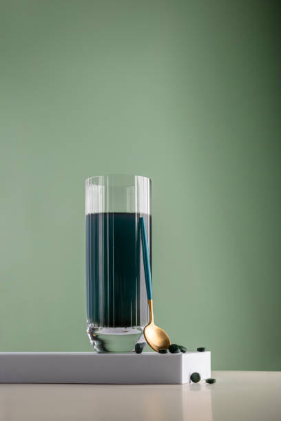 green detox drink with spirulina in a glass and pills on a minimalistic composition. vitamins, health and self care concept - healthy eating food and drink nutrition label food imagens e fotografias de stock