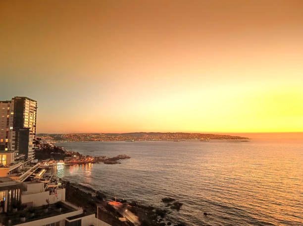 Coast on the Pacific Ocean in the city of Viña del Mar at sunset. In the background, the port and the city of Valparaiso, (UNESCO World Heritage Site). Chile. Coastline with beaches on the Pacific Ocean at sunset. Concon, Viña del Mar, Valparaiso region, Chile. vina del mar chile stock pictures, royalty-free photos & images