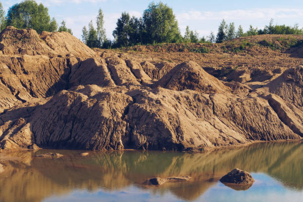 Flooded sand quarry. Cracked drought clay piles during the dry season. Bright yellow or orange texture sand color land. Stock background photography Sychevo mines. Volokolamsk district of Moscow region cantera de arena inundada. pilas de arcilla de sequía agrietadas durante la estación seca. tierra de color arena de textura amarilla o naranja brillante. foto de fondo de archivo minas sychevo. distrito de volokolamsk de la región de moscú