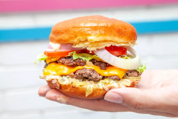 istock Double cheese beef burger with doughnut bun in the palm of a hand 1389431185