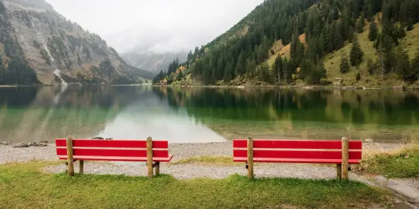 two red benches on the bank of Vilsalpsee lake in Tyrol, Austria