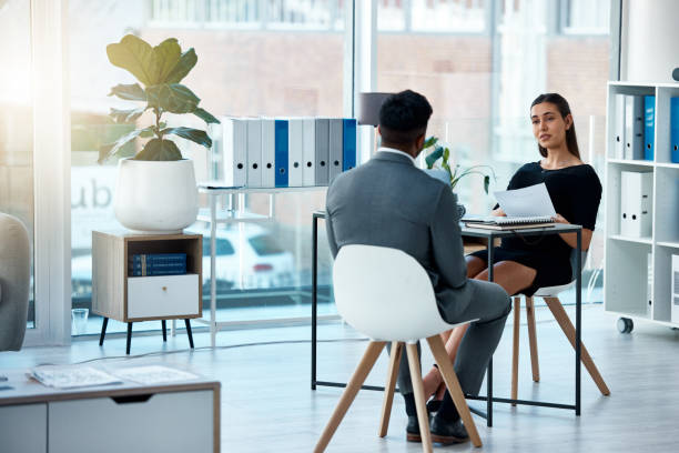 foto de una joven empresaria revisando un currículum de un solicitante durante una entrevista de trabajo en una oficina - entrevista fotografías e imágenes de stock