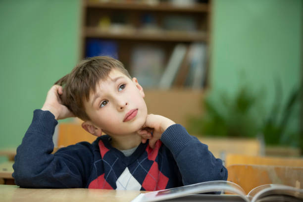 istock Elementary school boy in a classroom with a book. Child at school. 1389433777