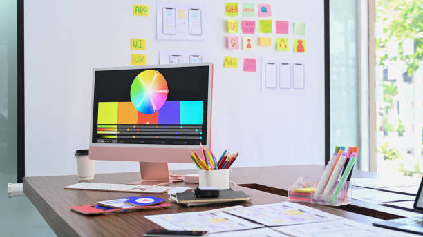 istock Modern computer with color swatches and wireframe sketches for mobile application on wooden table. 1389436324