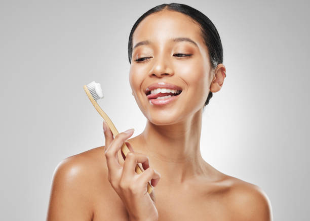 Studio shot of an attractive young woman sticking out her tongue while brushing her teeth against a grey background A bright smile looks good on me human tongue stock pictures, royalty-free photos & images