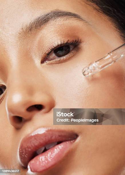 Portrait Of An Attractive Young Woman Applying Serum To Her Face Stock Photo - Download Image Now
