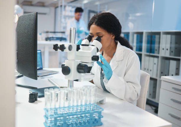 photo d��’une jeune employée de laboratoire analysant des échantillons au microscope - microscope laboratory scientist women photos et images de collection